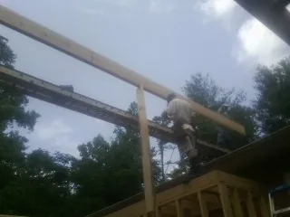 Carpenter setting a ridge beam over a new addition frame — Ice Dam Removal by Roofing Brothers in Mills River