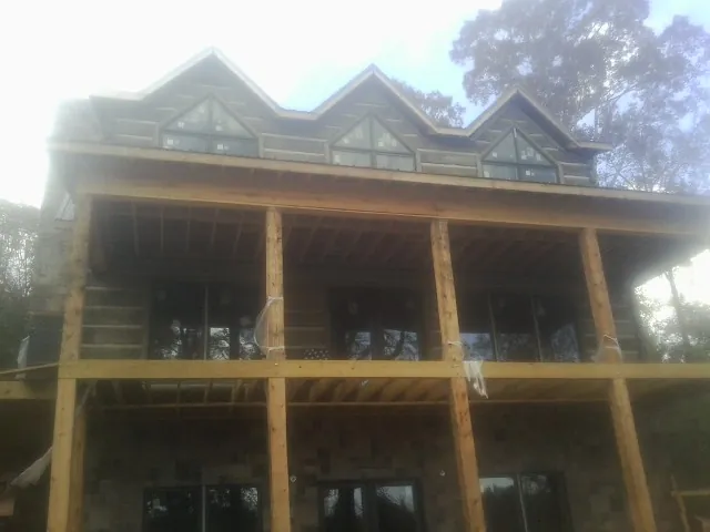 Dormers and porch framing on a large log home under construction — Roof Coating work by our crew in Mills River