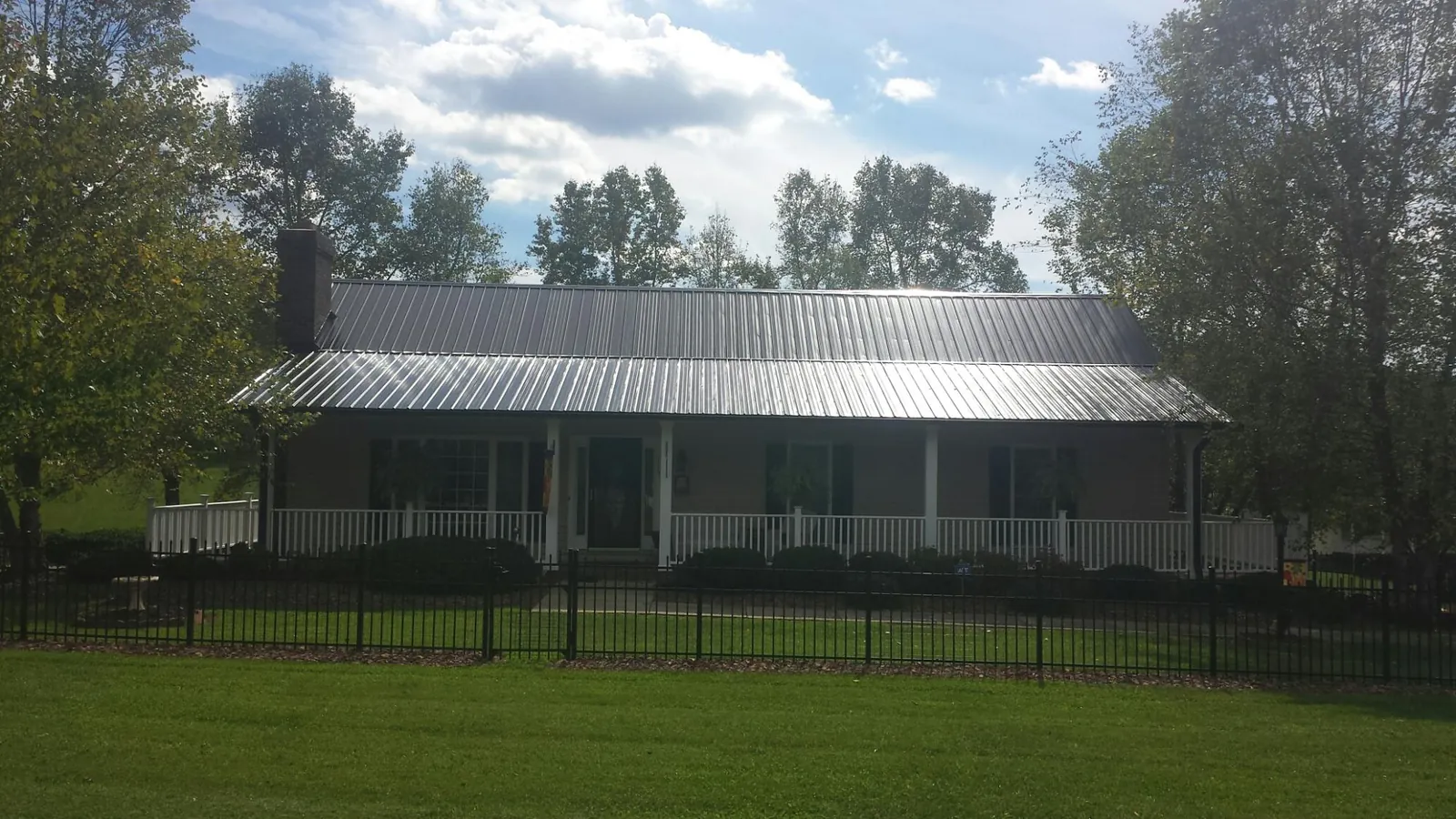 Gray metal roof on a brick ranch with a full width front porch — Gutter Guard Installation work by our crew in Mills River