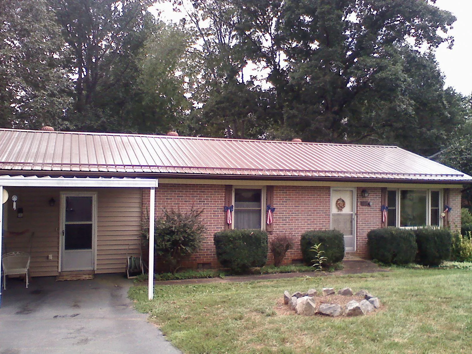 Bronze metal roof and carport on a brick ranch home — Roof Repair work by our crew in Mills River