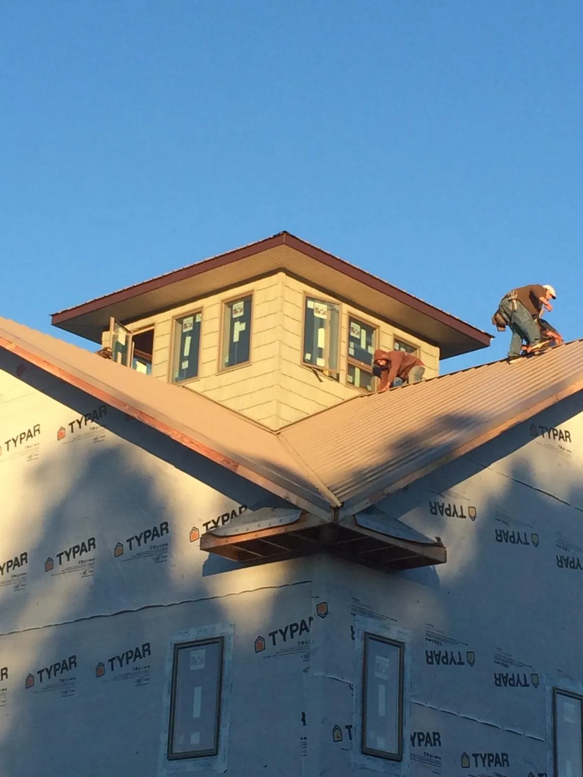 Roofers working around a rooftop cupola on a new metal roof at sunset — Roof Waterproofing in Mills River by Roofing Brothers